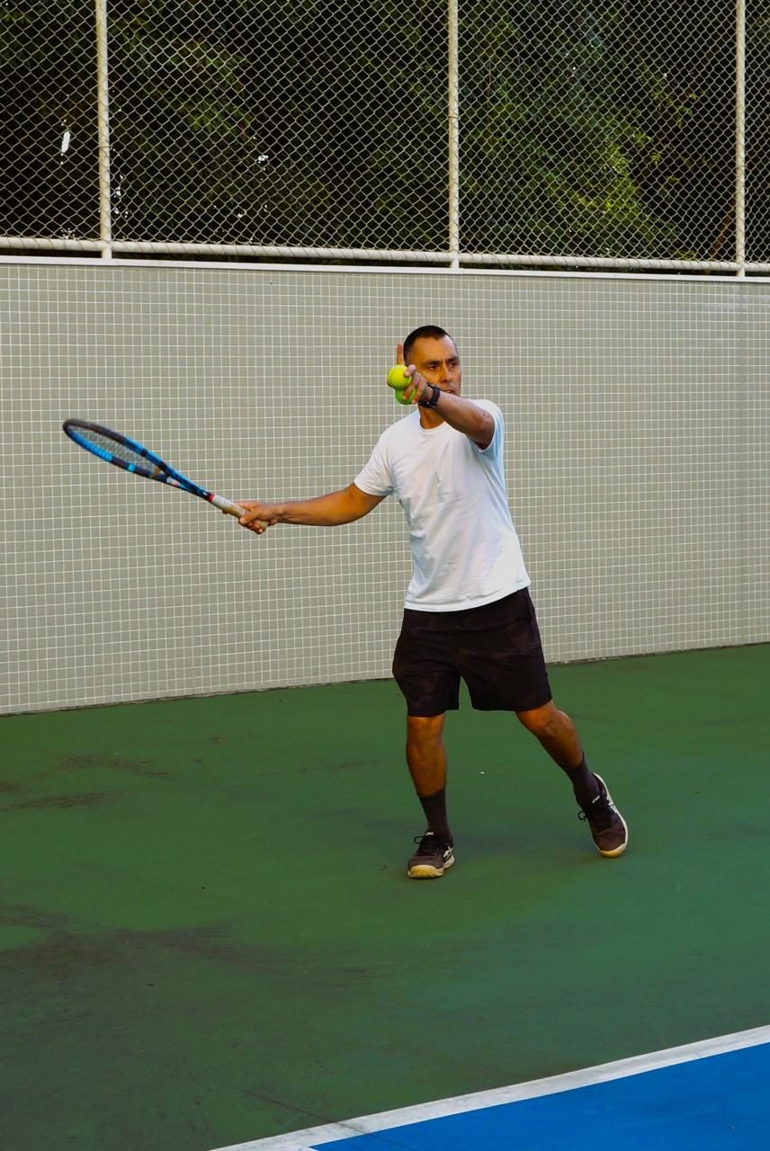 Professor em quadra, com a bola na mão, preparando um golpe